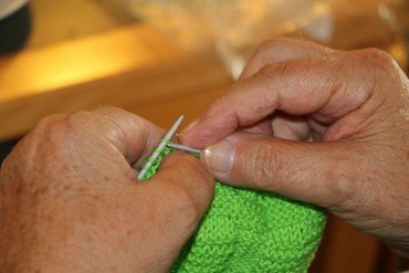 Billede af Hænder, der holder strikkepinde og strikketøj i grøn farve