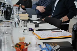 mennesker sidder ved bord, papir og blyant