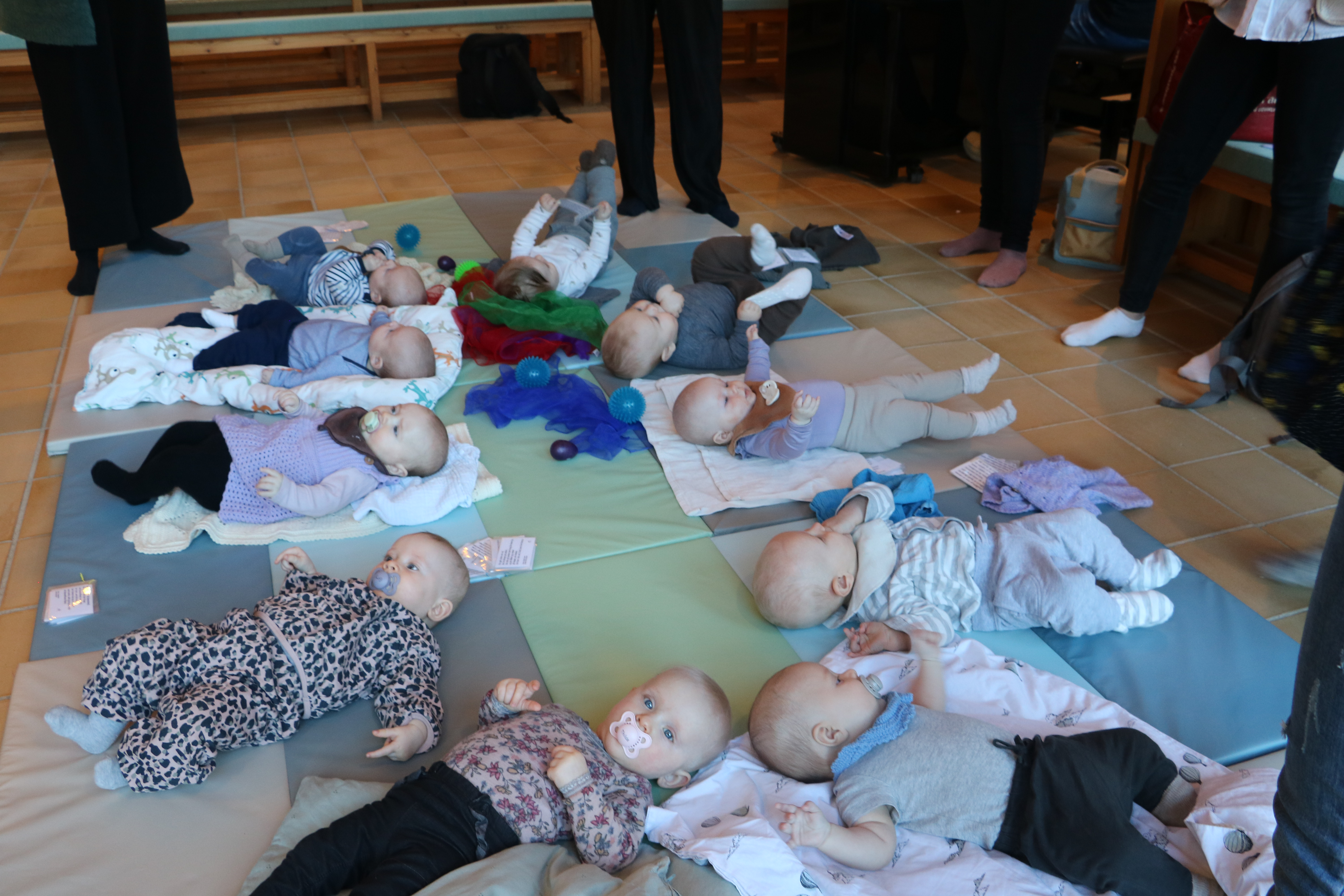 Billede af organist ved klaver. På klaveret sidder fire spædbørn