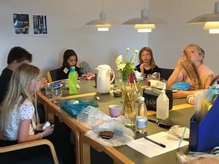 to piger og en ældre kvinde ser på salmebøgerne i kirken