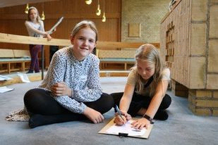 to piger sidder ved alteret og løser en opgave