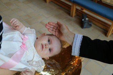 Barn i dåbskjole, der bliver døbt